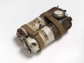 Mixed-media assemblage using rusty propane torch cannisters, cloth straps, wire and a pocketwatch...