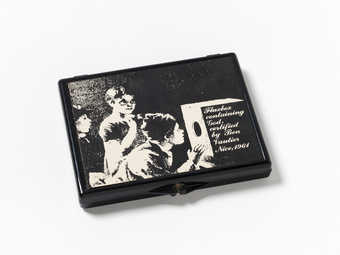 Black plastic box with black and white label printed with line art of children looking into a...