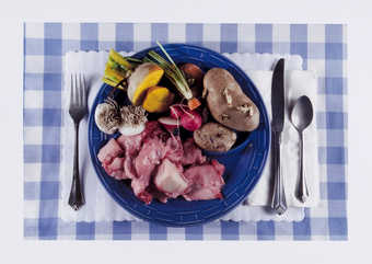 An image of a plate of waste food; sprouted potatoes, carrot tops, bones and sinew, radish roots,...