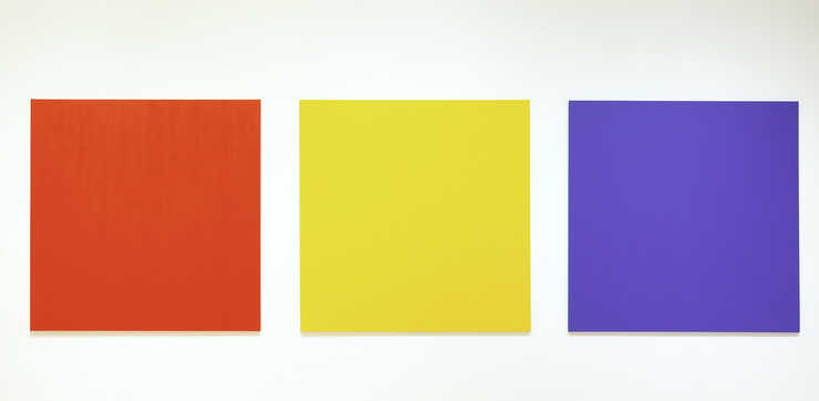 three canvases one red, one yellow, and one blue installed with a distance of 10 inches between...