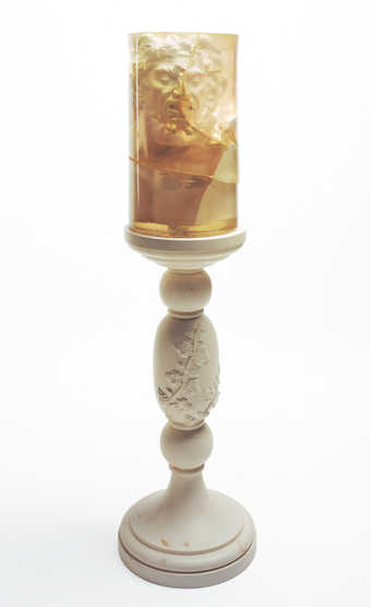 plaster cast bust encased in a cylinder of resin that sits upon a white pedestal.