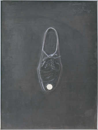 An image of the top view of a shoe, embossed in sheet lead, with a round mirror on the toe.