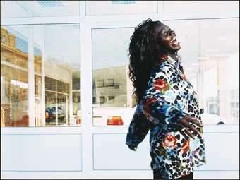 A woman bending backward with arms extending laughing in front of a store front