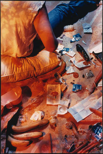 An image of the back of a woman who is putting condoms onto vegetables.