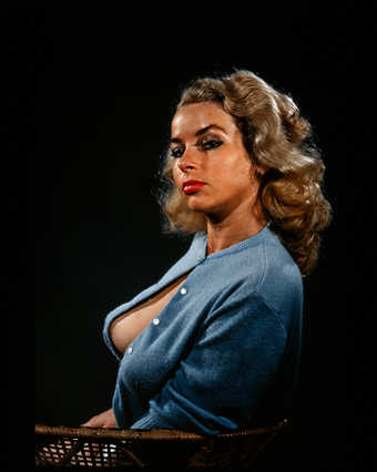 A profile view of a seated woman wearing a blue sweater.