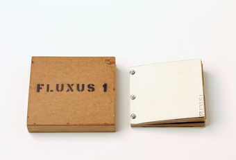 A wooden box with Fluxus I stenciled in black; the contents are bolted together.