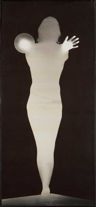 silhouette of a standing woman holding a globe of light