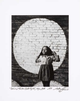 An image of a young girl in front of a brick wall, with a large light colored circle.