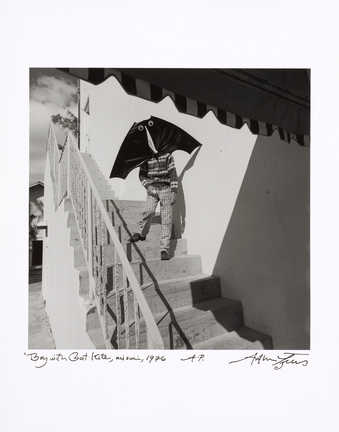 An image of a boy carrying a kite, which covers his face, down a flight of steps