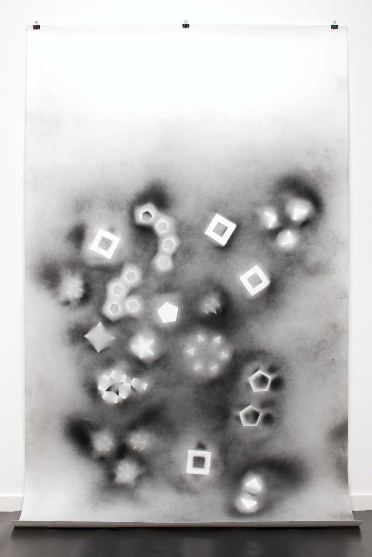 A drawing created by setting origami foldings onto a white sheet of paper and spraying with black...