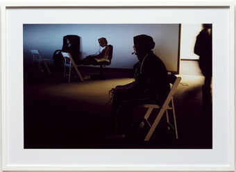 An image of two young men sitting in folding chairs, playing video games.  C-Print on Kodak...
